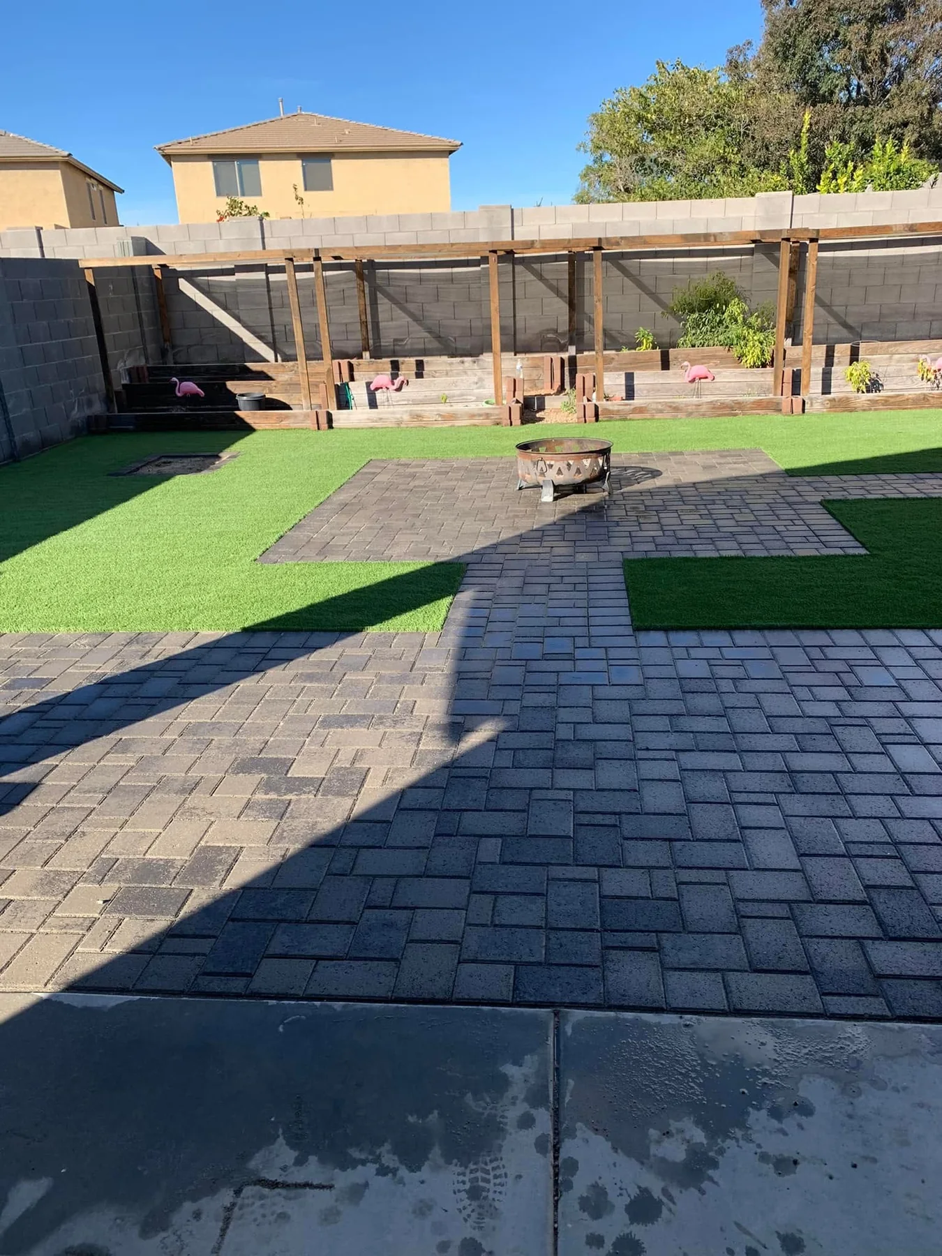 Artificial turf, paver walkways, a fire pit, and raised garden planters